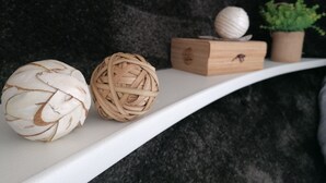A shelf with two woven balls and a small wooden box with a plant.