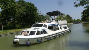 A narrowboat with a covered deck and a cabin, floating on a canal.