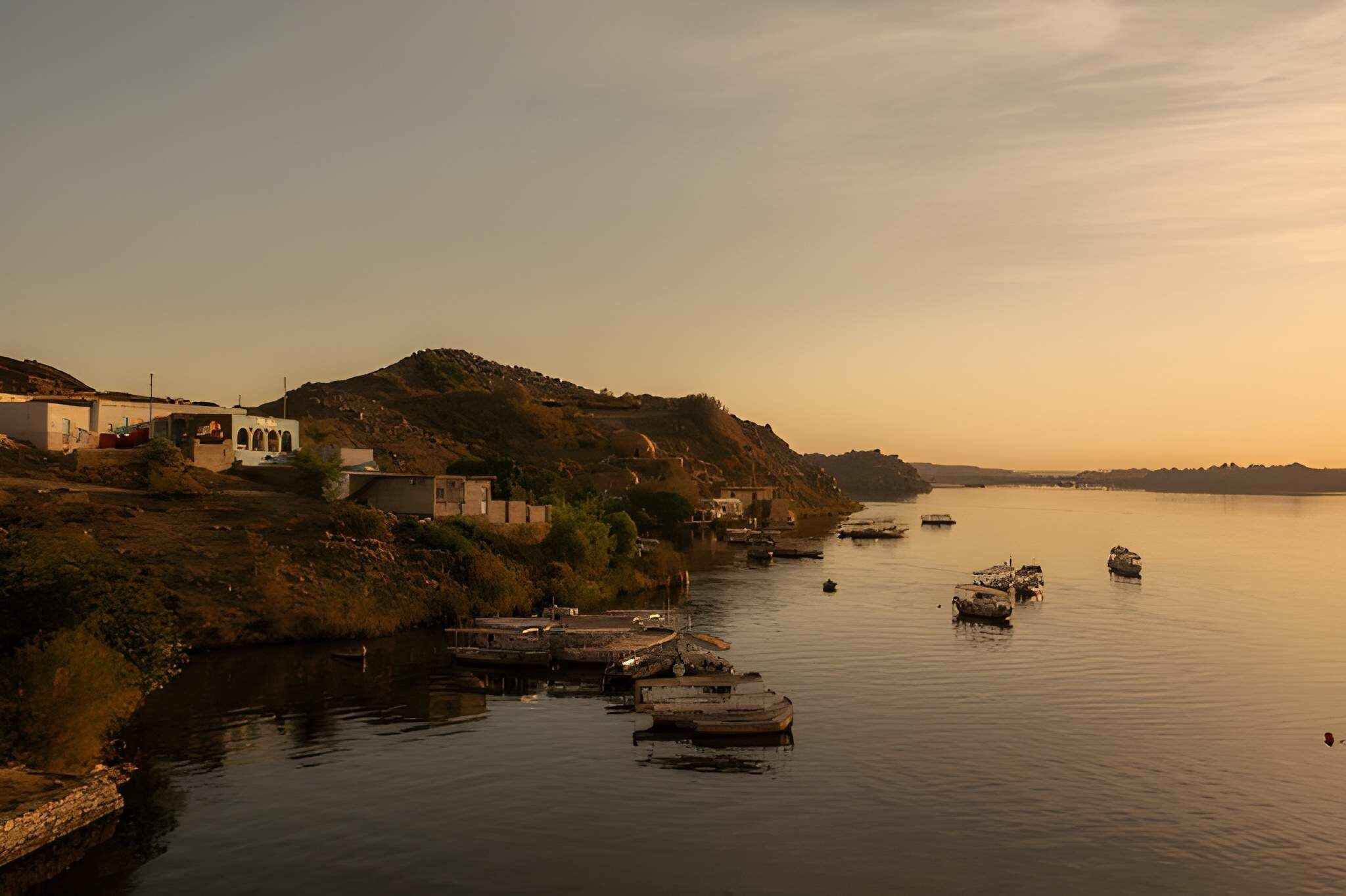 Un pueblo ribereño con barcos amarrados a la orilla y edificios en la ladera de la colina.