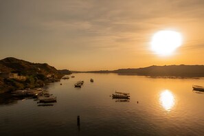 A calm river with boats, a distant shoreline, and a sunset. - Noprea Boutique Hotel (Aswan)