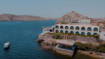 A coastal building with multiple arched windows, a dock, and a boat.