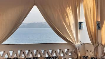 Habitación con vista al mar, que cuenta con techo de madera, un sofá estampado y una mesa.