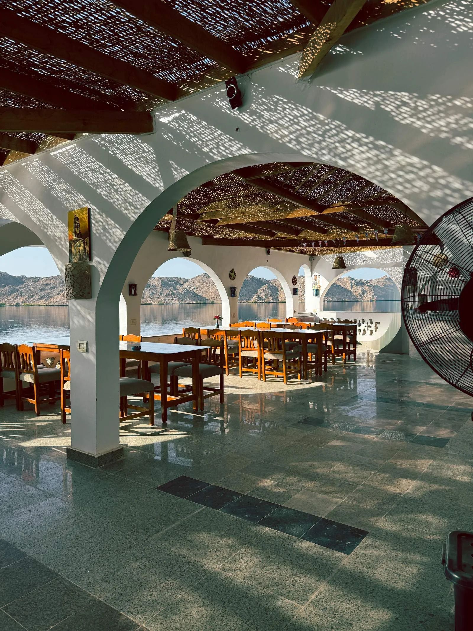 An indoor dining area with tables and chairs, large windows, and a view of mountains.