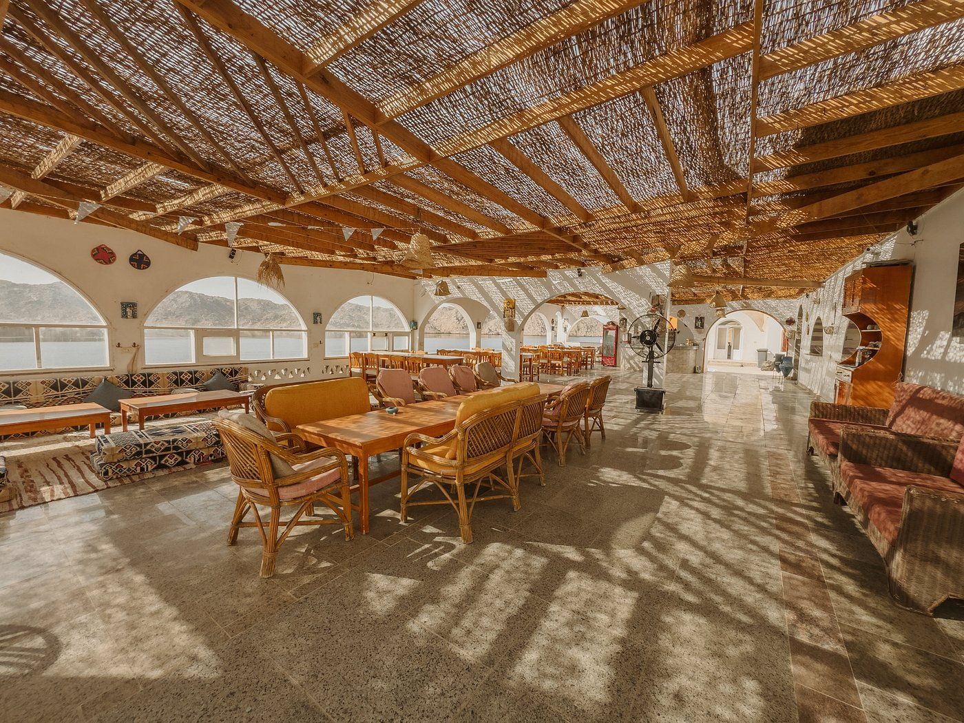 Un intérieur agrémenté de fenêtres en arc de cercle, de meubles en bois et d’un plafond en chaume.