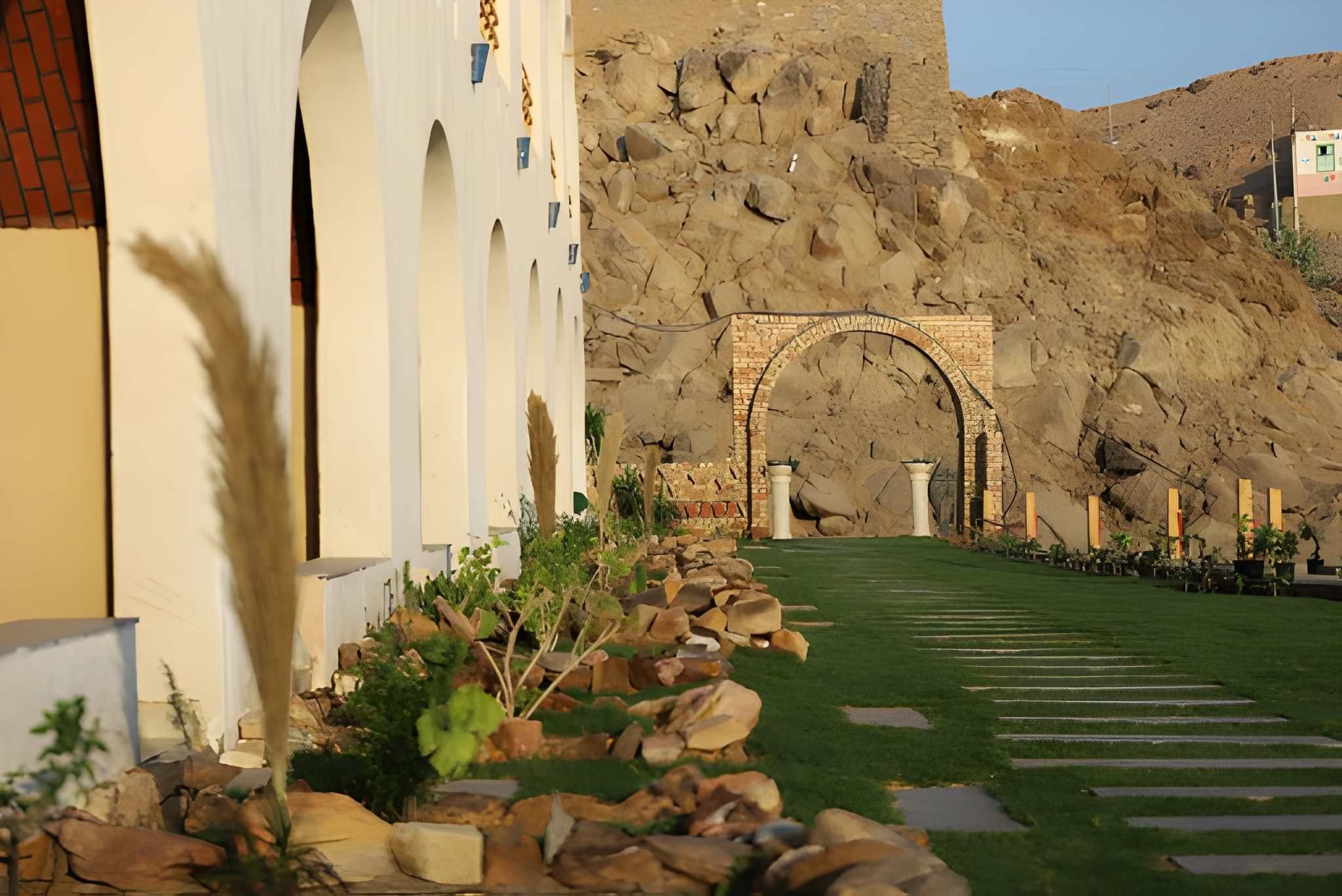 A courtyard with a stone archway leading to a building with white columns.