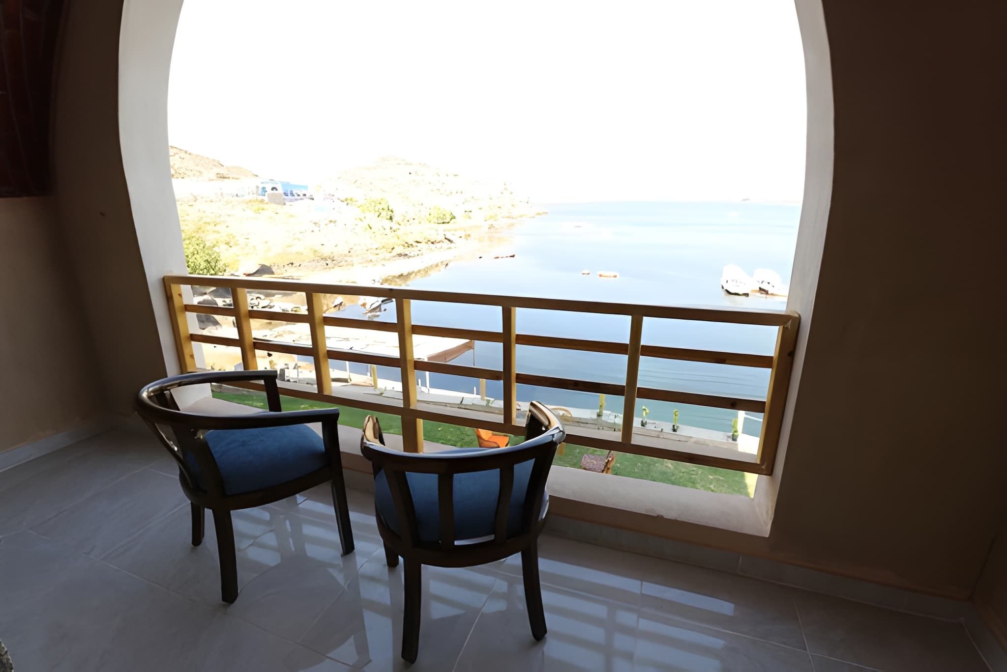 A balcony with two chairs and a view of a coastal area.