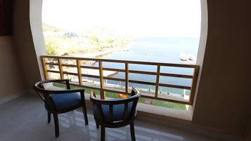 A balcony with two chairs and a view of a coastal area.