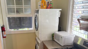 Une cuisine équipée d’une cuisinière, d’un four à micro-ondes, d’un lave-linge et d’une fenêtre avec des stores.