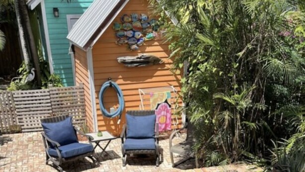 Une piscine bordée de briques, entourée de chaises longues et d’une terrasse en bois.