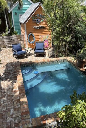 A swimming pool with a brick border, surrounded by lounge chairs and a wooden deck. - 4 blocks from Duval and 7 blocks from the beach (Key West)