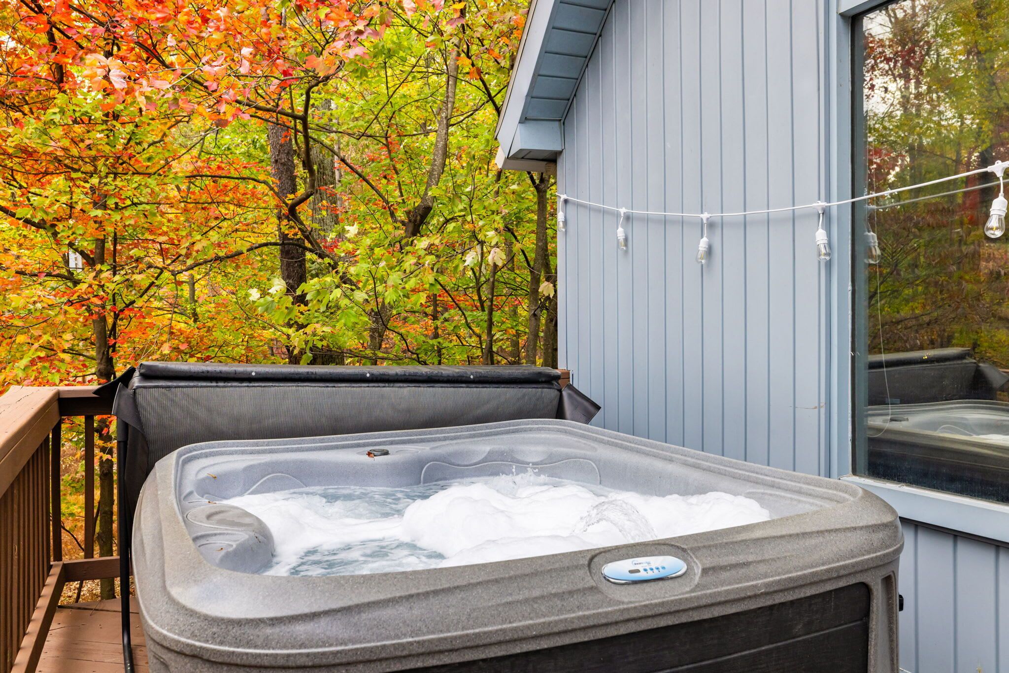 Ein Whirlpool auf einer Holzterrasse, im Hintergrund Herbstlaub.