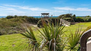 A gazebo with a view of the sea, surrounded by greenery and a grassy area.
