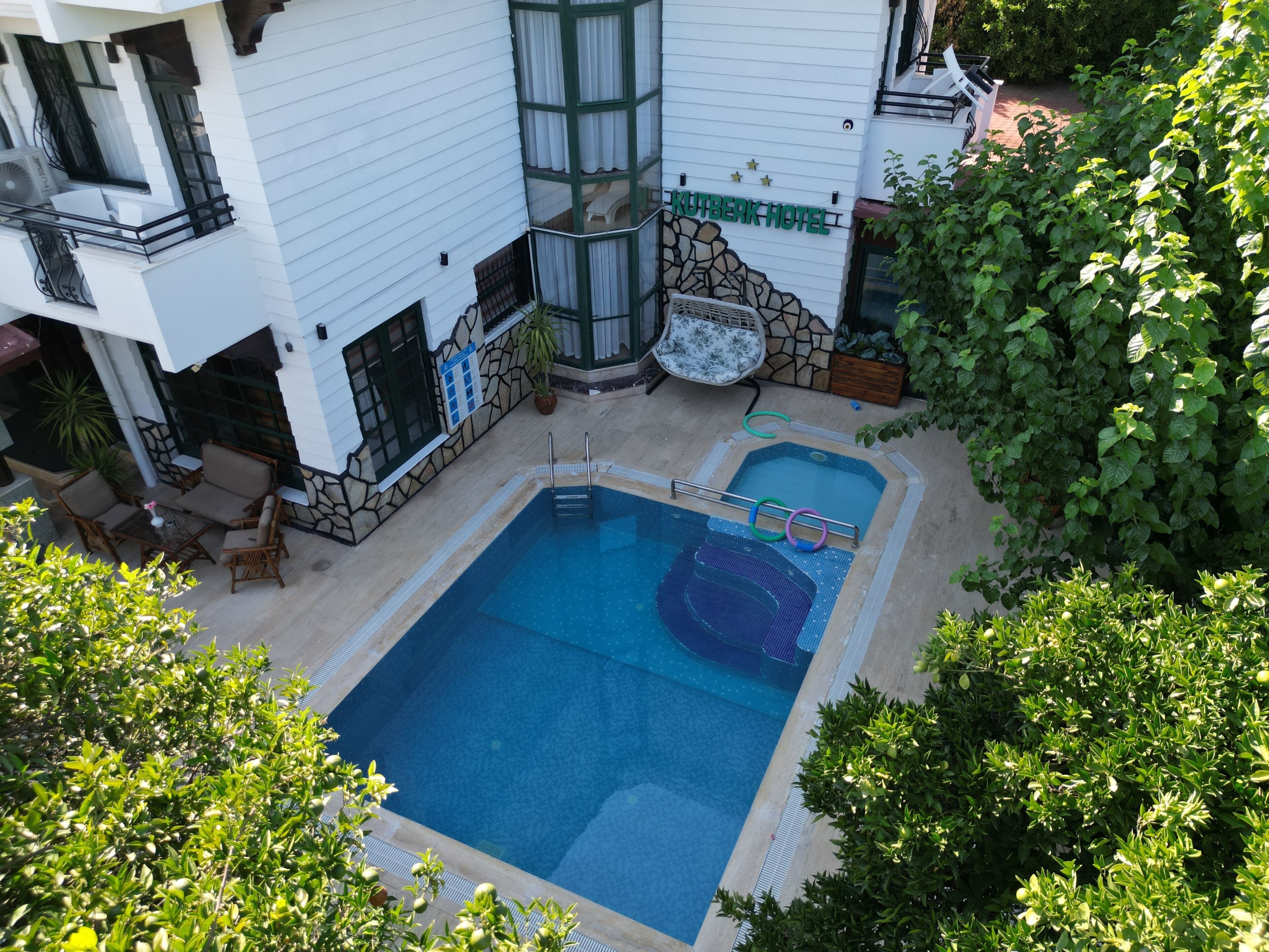 A hotel with a swimming pool, outdoor seating, and a stone facade.