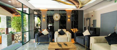 A modern lobby with a marble floor, a wooden coffee table, and a mix of black and white sofas.