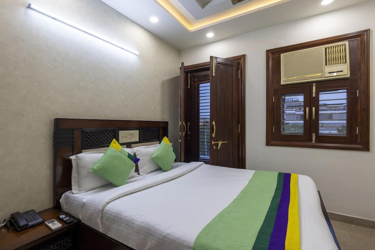A neatly arranged bedroom with a bed, bedside table, and a window with a wooden frame.