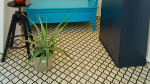 Una habitación con un sofá azul, un armario negro, una planta en maceta y un cuadro en la pared.