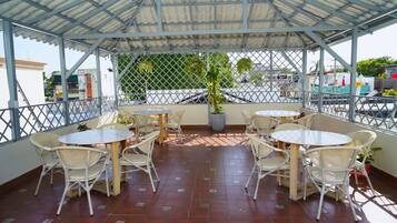 An outdoor patio with tables and chairs, a covered area, and a view of the street.
