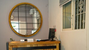 Una recepción con detalles de madera, un espejo redondo encima y una silla azul a la derecha.