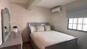 Un dormitorio con cama, cómoda, espejo y ventana.