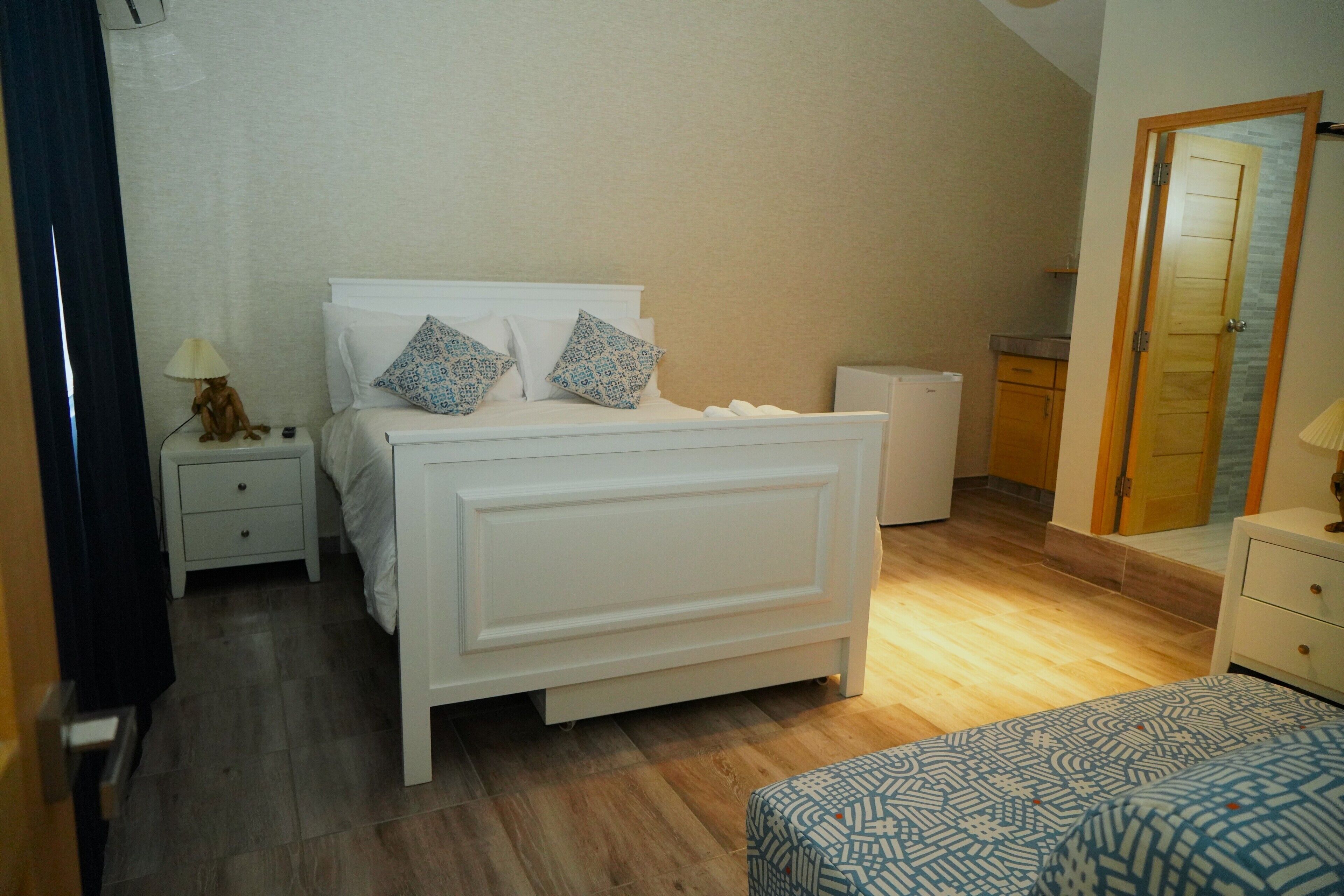 Un dormitorio con cama, mesitas de noche, cómoda y una puerta.