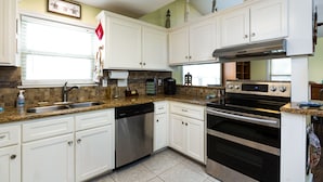 A kitchen with white cabinets, a dishwasher, an oven, and a granite countertop.