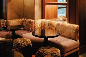 A corner seating area with floral upholstery, a round table, and patterned cushions. - Hotel Hana (Paris)