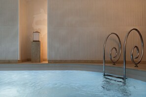 A swimming pool with metal handrails and a tiled floor. - Hotel Hana (Paris)