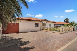 A residential property with a paved driveway, a gated entrance, and a red-tiled roof. - Felicidad: Stunning 3BR Retreat with Private Pool (Oranjestad)