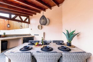 A dining area with a wooden ceiling, a hanging light fixture, and a potted plant. - Felicidad: Stunning 3BR Retreat with Private Pool (Oranjestad)