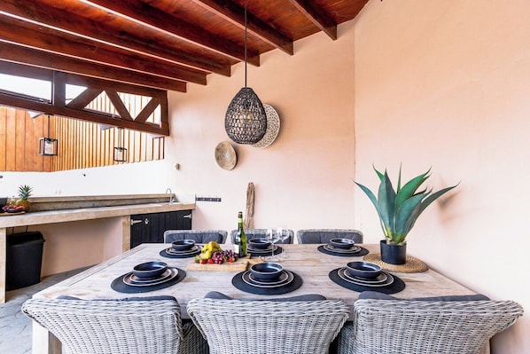 Un comedor con techo de madera, lámpara colgante y planta en maceta.