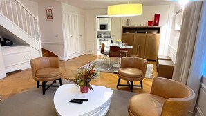 A living room with a white coffee table, two brown leather chairs, a remote control, and a vase with flowers. - L'appartement Pierre Charron C (Paris)