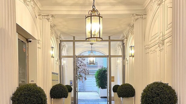 A grand hallway with a red carpet, white columns, and a chandelier. - L'appartement Pierre Charron C (Paris)