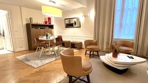 A modern living room with a dining area, wooden flooring, and a large window with curtains. - L'appartement Pierre Charron C (Paris)