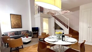 A modern living room with a round dining table, comfortable seating, a staircase, and a television. - L'appartement Pierre Charron C (Paris)