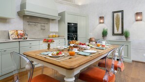Un comedor con una mesa de madera dispuesta para el desayuno, rodeada de sillas transparentes.