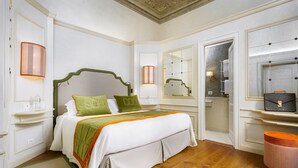 Un dormitorio elegante con una cama grande, un espejo y un tocador con una maleta.