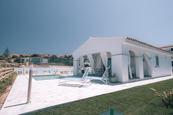Una villa moderna con piscina, area relax esterna e vista sul paesaggio circostante.
