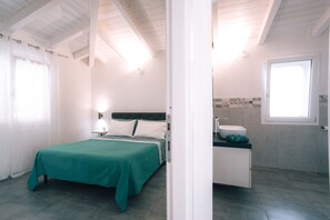 Una camera da letto con un letto, un comodino e un bagno con lavandino e specchio.