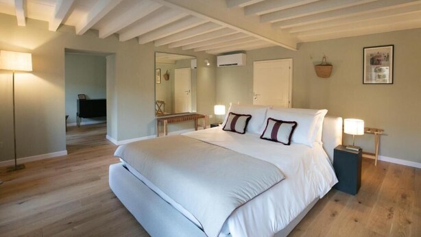 A bedroom with a large bed, a bedside table, a lamp, and a mirror. - Luxury Apartment with view on Piazza Pitti (Firenze)