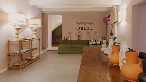A modern living room with a green sofa, a wooden coffee table, and decorative vases. - Luxury Apartment with view on Piazza Pitti (Firenze)