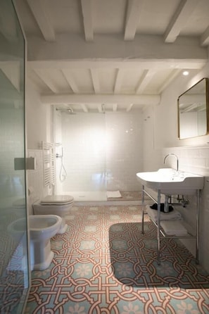 A bathroom with a patterned floor, a white sink, and a glass shower enclosure. - Luxury Apartment with view on Piazza Pitti (Firenze)