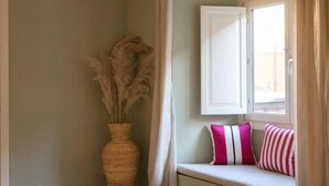 A corner of a room with a woven basket containing pampas grass, a white cabinet, and a bench with striped pillows. - Luxury Apartment with view on Piazza Pitti (Firenze)