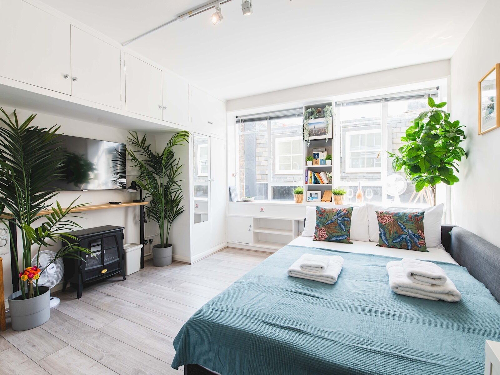 Un dormitorio moderno con cama, mesitas de noche, armario, escritorio y ventana con vistas.
