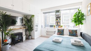 A modern bedroom with a bed, bedside tables, a wardrobe, a desk, and a window with a view. - Stylish & cozy City Studio close to Hyde Park - Pass the Keys (London)