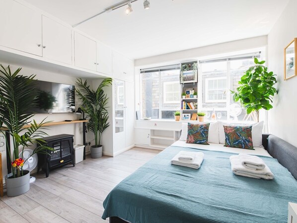 A modern bedroom with a bed, bedside tables, a wardrobe, a desk, and a window with a view.