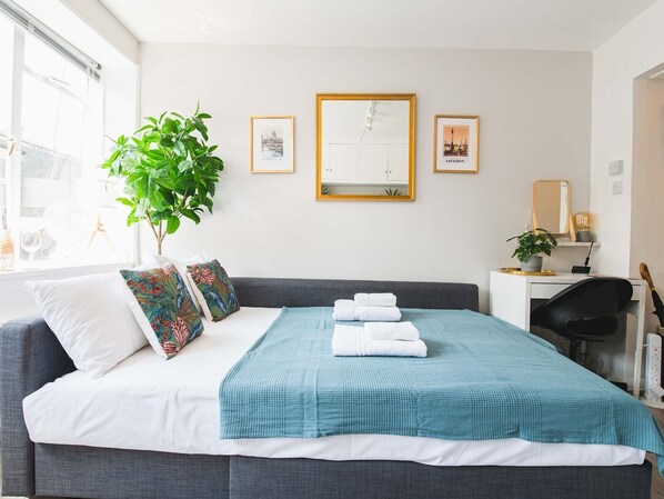 Et moderne hotelværelse med en stor seng, et skrivebord og en potteplante.