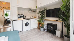 A compact kitchen with a washing machine, microwave, and a small dining area. - Stylish & cozy City Studio close to Hyde Park - Pass the Keys (London)