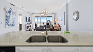 Una cocina moderna con un lavamanos doble, una zona de comedor con vistas y una araña.