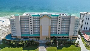 Un hotel grande con varios pisos, una entrada principal y un área de piscina.