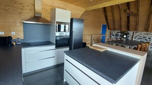 Una cocina moderna con una isla central, horno empotrado y una pared decorativa de piedra.